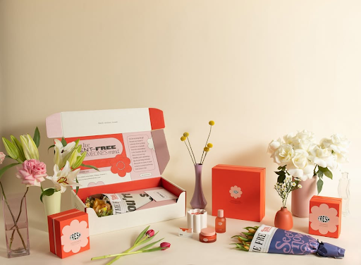 An open gift mailer surrounded by âFresh Sendsâ flowers in vases, candles, perfume, and hand cream.-317639524719