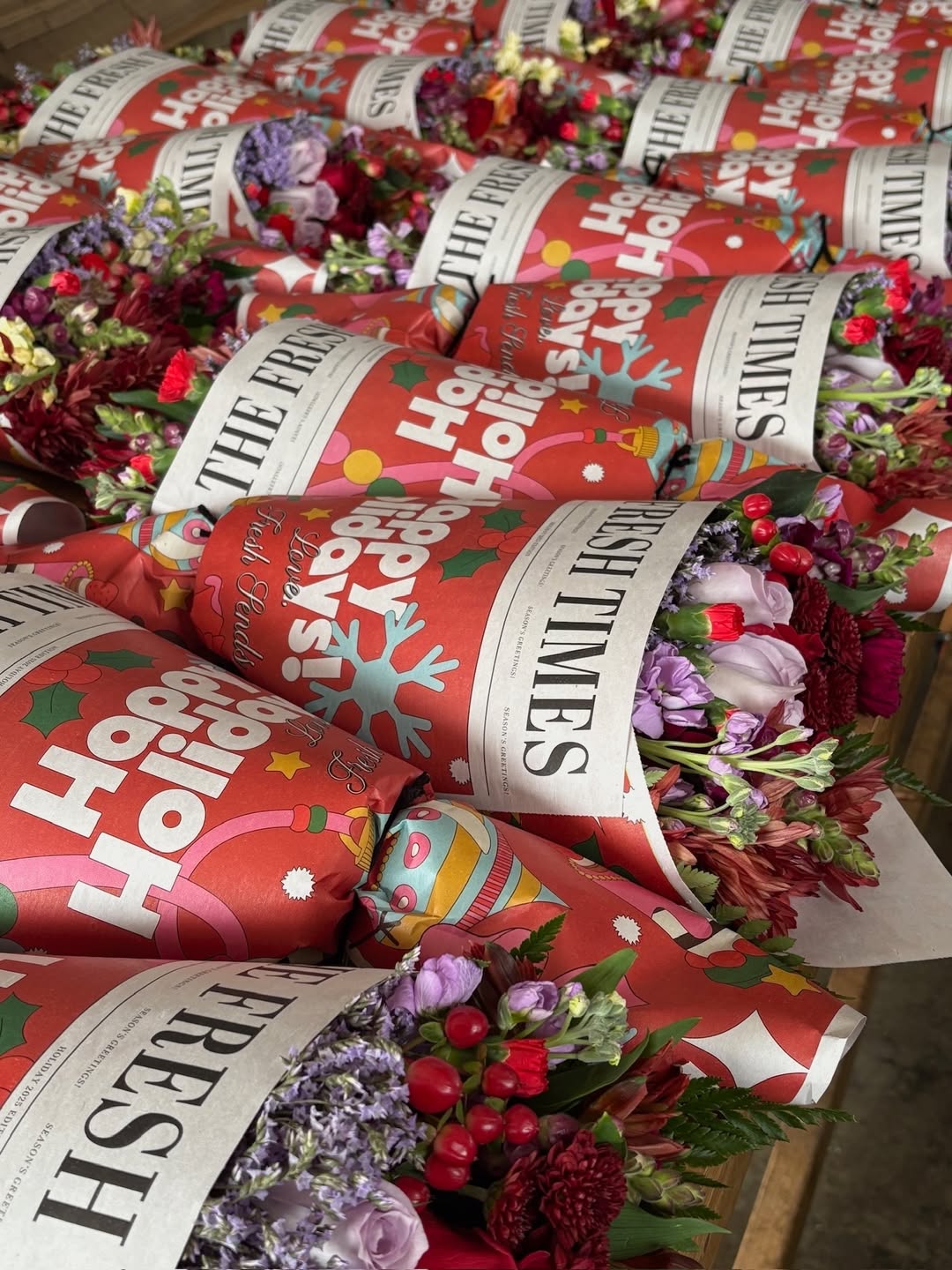 Multiple holiday Fresh Sends bouquets wrapped in red paper with festive illustrations, ready for delivery.-319291130223
