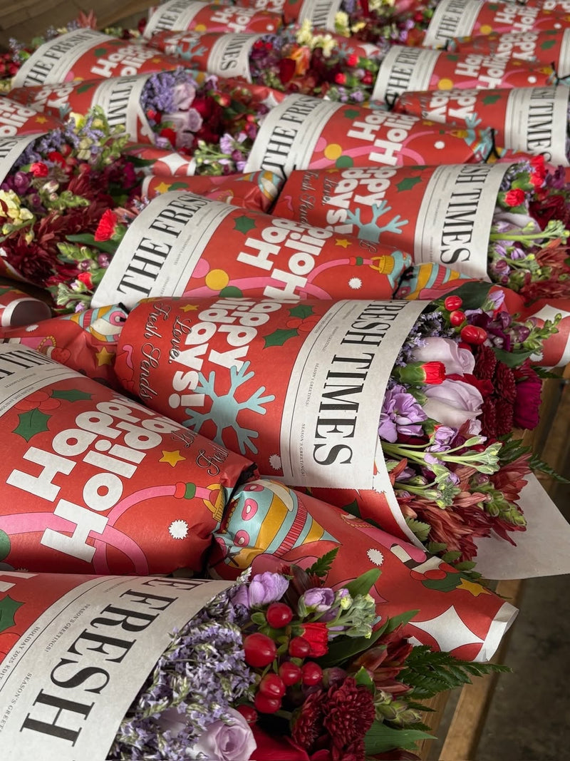 Multiple holiday Fresh Sends bouquets wrapped in red paper with festive illustrations, ready for delivery.