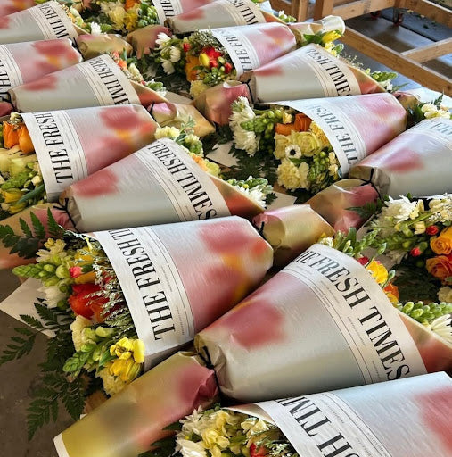 	Fresh Sends anniversary bouquets wrapped in custom “The Fresh Times” paper, featuring roses, daisies, and lisianthus.-317259383151