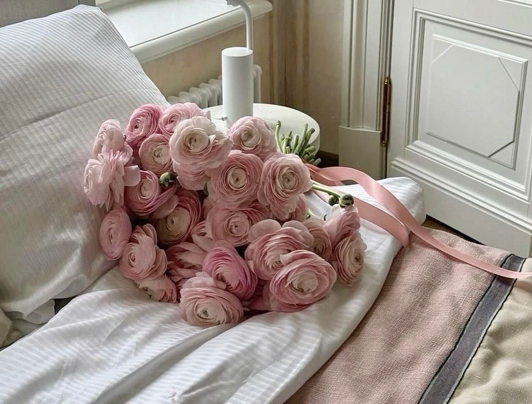 A bouquet of pink Ranunculus by Fresh Sends sitting on the bed.-318829199727