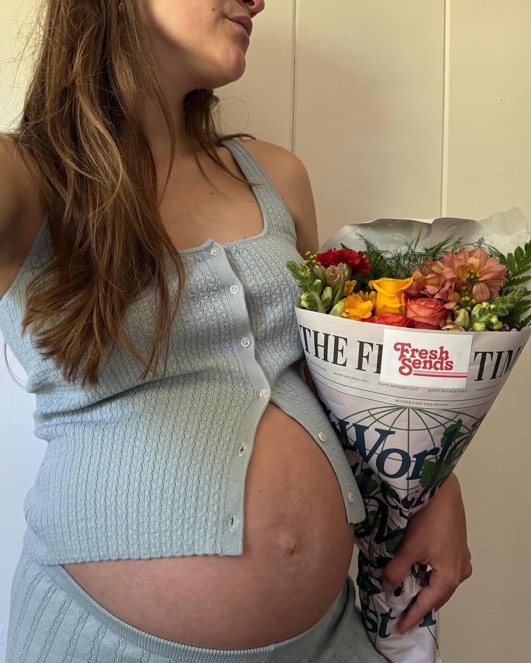 Pregnant woman holding a Fresh Sends flower bouquet wrapped in newspaper packaging.-320446792047