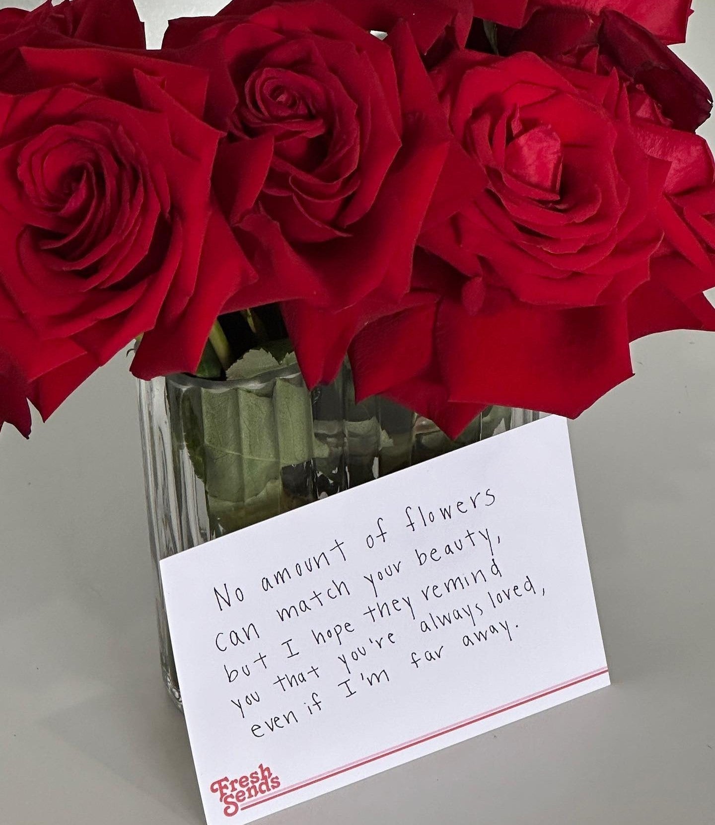 Fresh Sends’ bouquet of red roses in a clear glass vase with a card expressing long-distance love.-318676238703