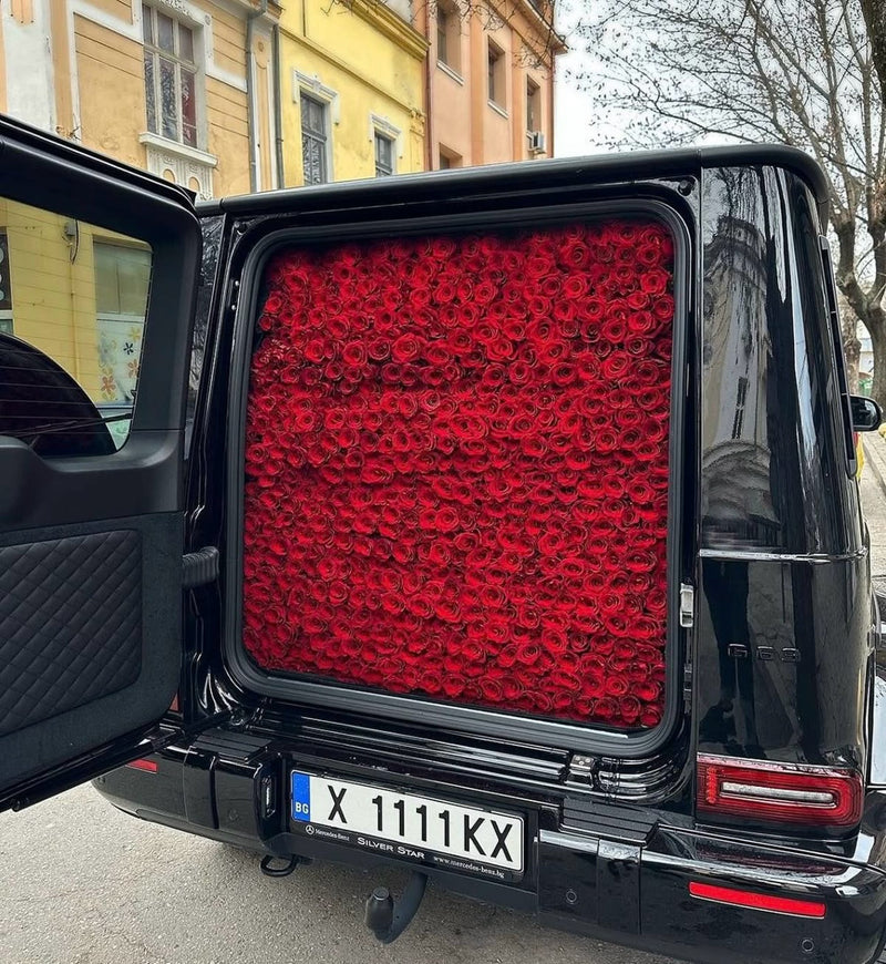 Black SUV with open trunk full of red roses from Fresh Sends.