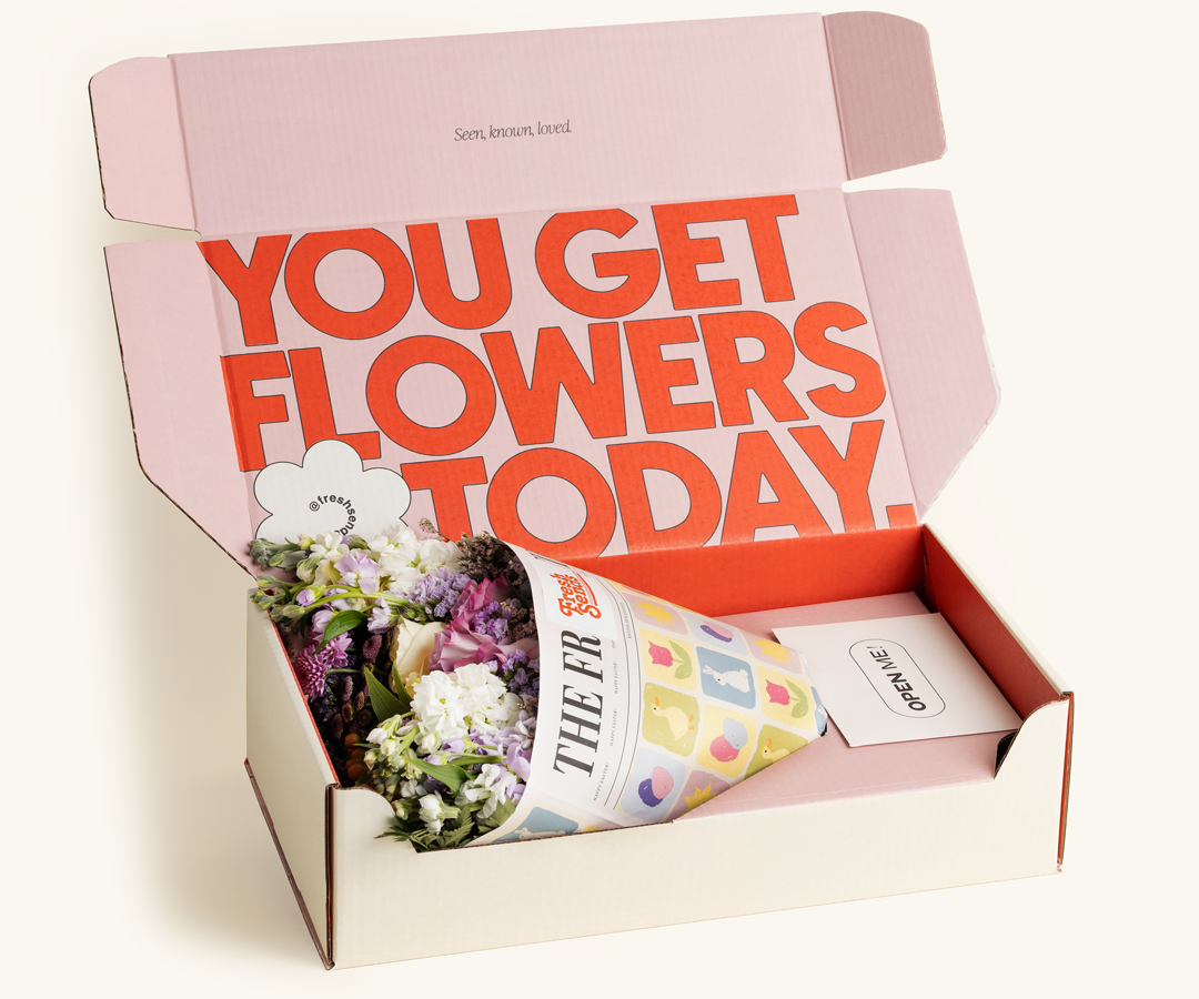 A glass vase with pink tulips and a wrapped bouquet of orange tulips on a neutral background.